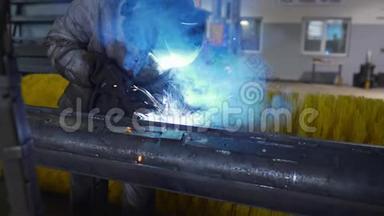 工厂车间内戴防护面罩和工作服的焊工焊接金属结构，工厂内从事金属加工